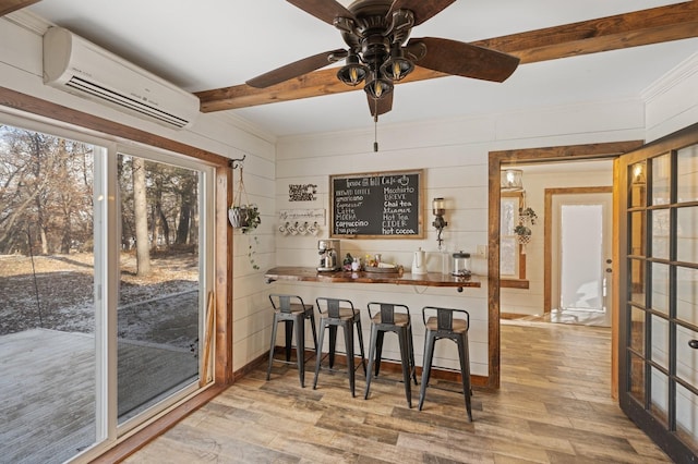 bar with beamed ceiling, wooden walls, a wall mounted AC, and light wood-type flooring