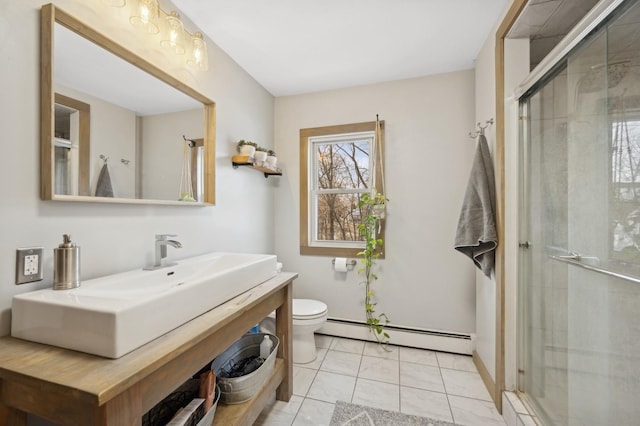 bathroom featuring sink, tile patterned flooring, a baseboard heating unit, a shower with shower door, and toilet