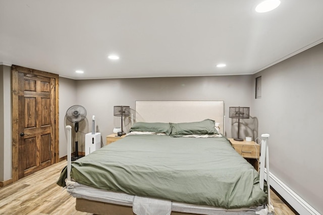 bedroom featuring crown molding, light hardwood / wood-style flooring, and baseboard heating