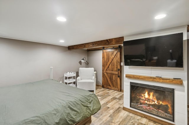 bedroom with a barn door and light wood-type flooring