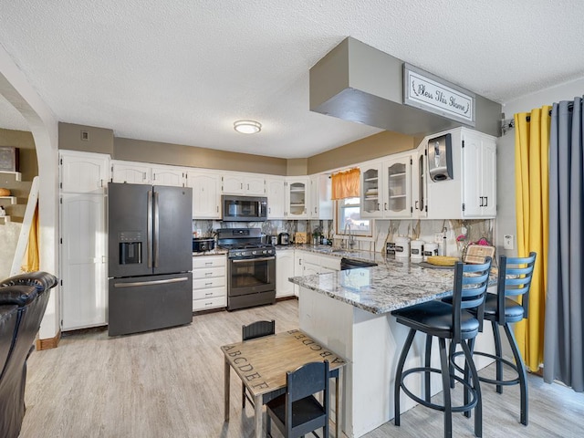 kitchen featuring tasteful backsplash, appliances with stainless steel finishes, white cabinets, and a textured ceiling