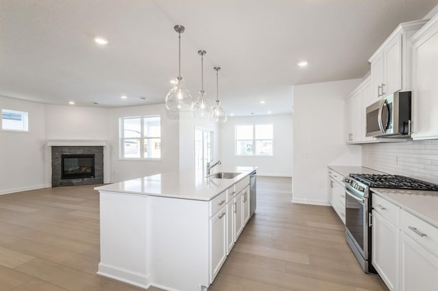 kitchen featuring a center island with sink, stainless steel appliances, white cabinets, and sink