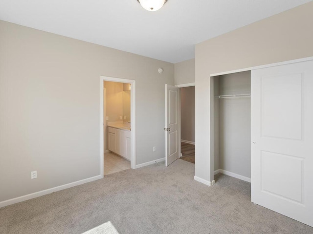 unfurnished bedroom featuring light colored carpet, ensuite bathroom, and a closet