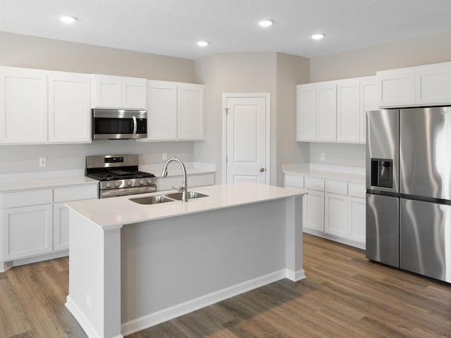 kitchen with hardwood / wood-style flooring, stainless steel appliances, a kitchen island with sink, white cabinets, and sink