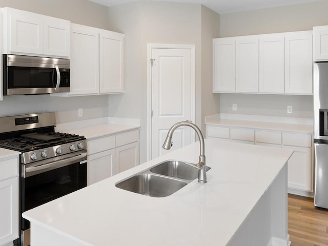 kitchen with an island with sink, white cabinets, appliances with stainless steel finishes, and sink