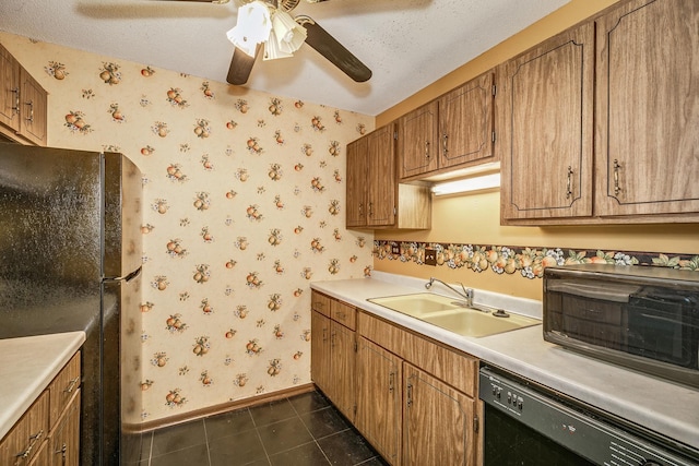 kitchen with sink, a textured ceiling, dark tile patterned floors, and black appliances