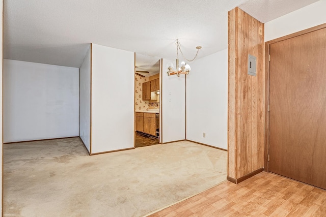 carpeted empty room with a chandelier and a textured ceiling