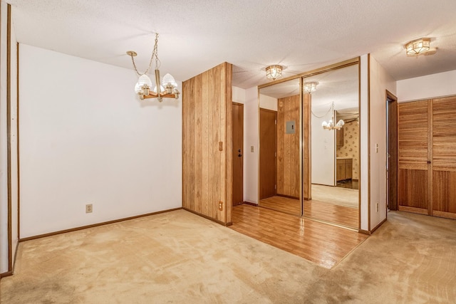 unfurnished room with a textured ceiling, a chandelier, and carpet flooring