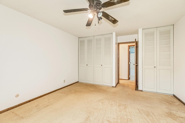 unfurnished bedroom featuring ceiling fan, light colored carpet, and multiple closets