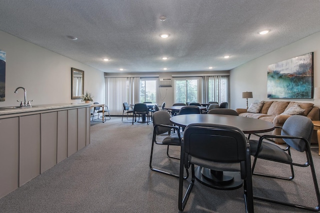 dining area featuring light colored carpet, sink, and a textured ceiling