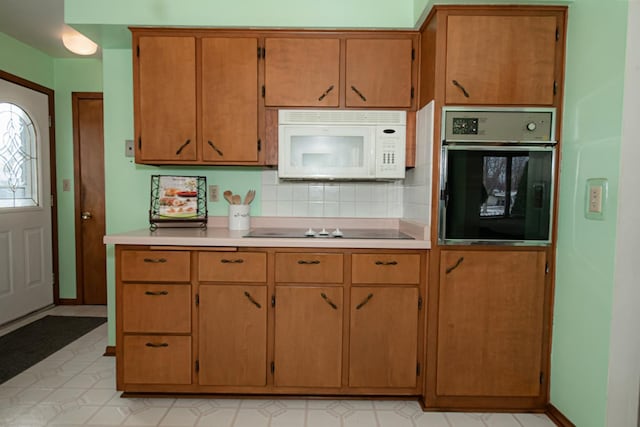 kitchen featuring black electric stovetop, decorative backsplash, and stainless steel oven