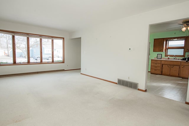 empty room featuring a healthy amount of sunlight, ceiling fan, and light carpet