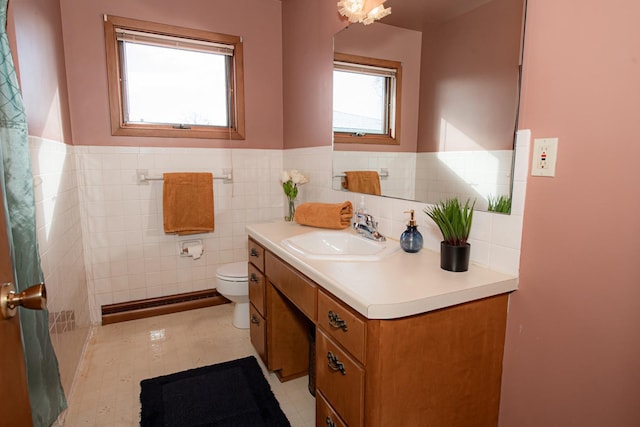 bathroom with tile walls, a wealth of natural light, vanity, and toilet