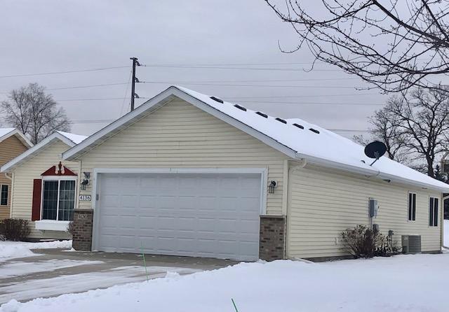 view of snowy exterior with cooling unit and a garage