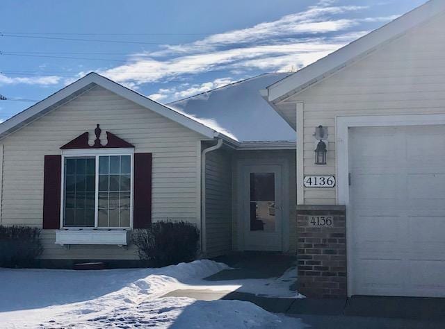 snow covered property entrance with a garage