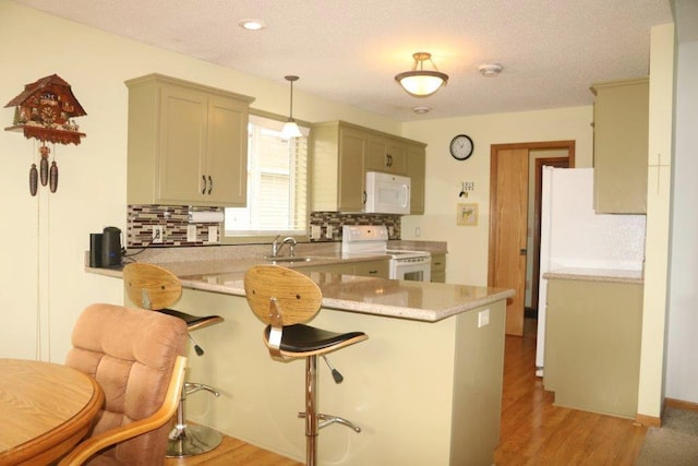 kitchen with pendant lighting, a kitchen breakfast bar, light hardwood / wood-style floors, kitchen peninsula, and white appliances