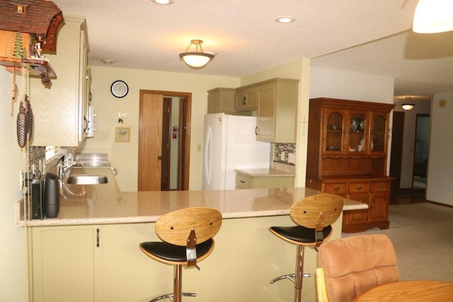 kitchen with white appliances, kitchen peninsula, sink, and a breakfast bar area