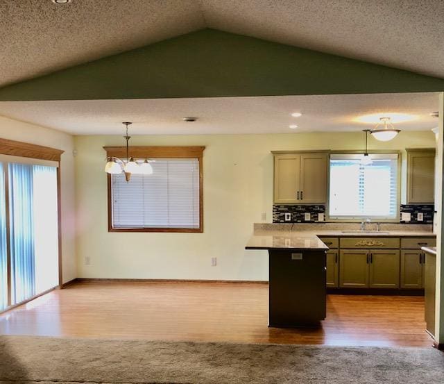 kitchen with a kitchen island, decorative light fixtures, sink, decorative backsplash, and plenty of natural light