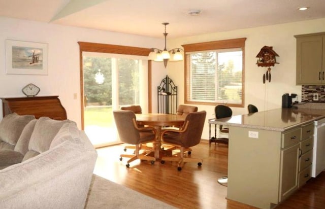 dining area featuring hardwood / wood-style flooring, vaulted ceiling, and an inviting chandelier