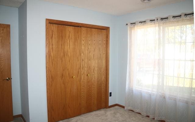 unfurnished bedroom with light colored carpet and a closet