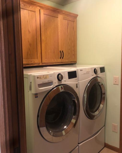 clothes washing area featuring cabinets, tile patterned floors, and separate washer and dryer