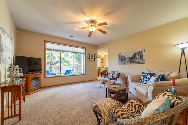 carpeted living area featuring a textured ceiling, visible vents, a ceiling fan, and baseboards