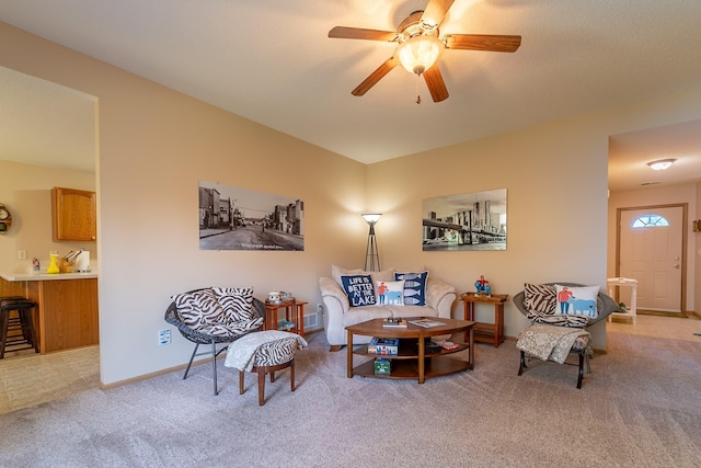 living area featuring light colored carpet, ceiling fan, and baseboards