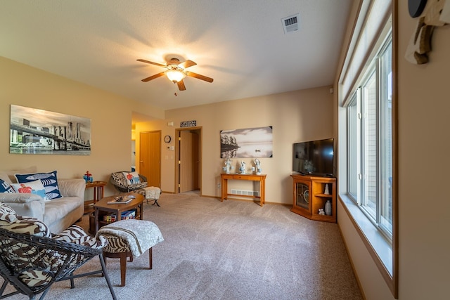 living room with a ceiling fan, carpet, visible vents, and baseboards