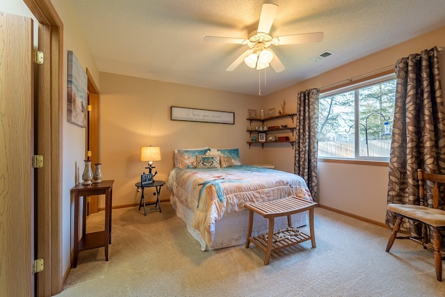 bedroom with visible vents, a ceiling fan, light carpet, a textured ceiling, and baseboards