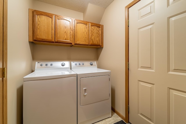 laundry room with cabinet space, a textured ceiling, and separate washer and dryer