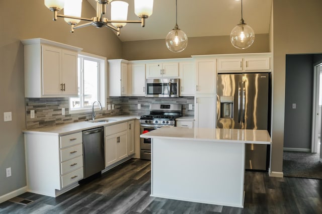 kitchen with a center island, decorative light fixtures, decorative backsplash, white cabinets, and appliances with stainless steel finishes