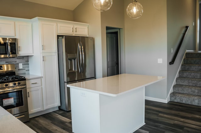 kitchen featuring dark hardwood / wood-style floors, hanging light fixtures, stainless steel appliances, backsplash, and white cabinets