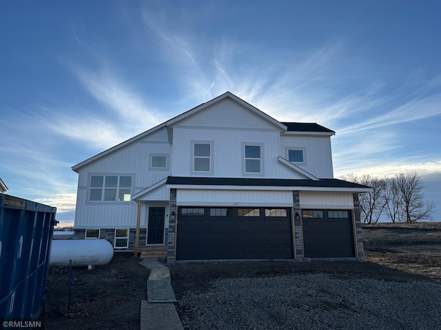 view of front facade featuring a garage, stone siding, and driveway