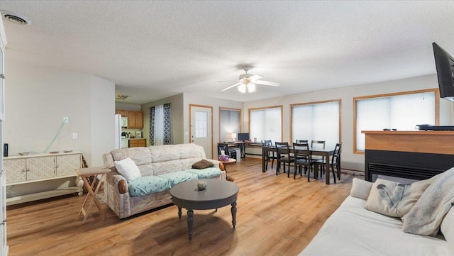 living room with visible vents, plenty of natural light, a textured ceiling, and light wood finished floors