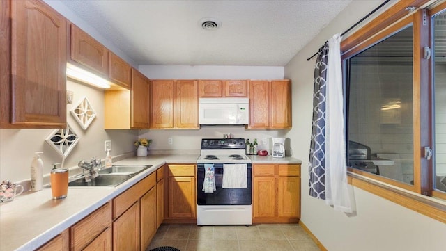 kitchen featuring light countertops, white appliances, a sink, and visible vents