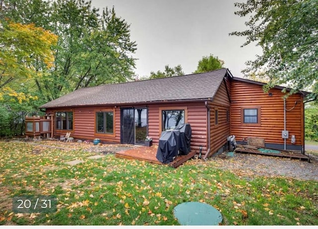 rear view of property featuring faux log siding, a yard, a shingled roof, and a wooden deck