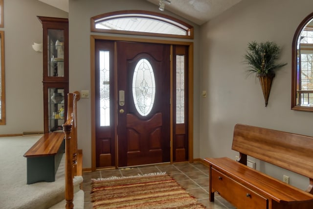 entryway with light tile patterned floors, a wealth of natural light, and vaulted ceiling