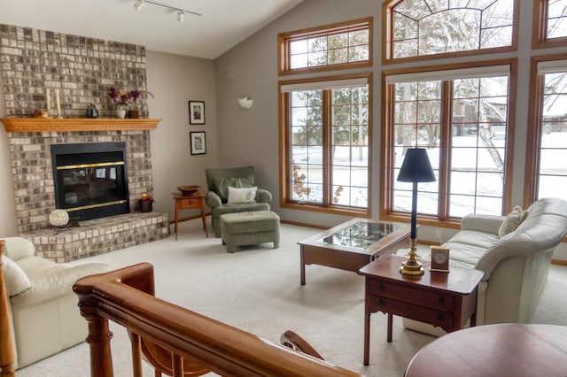 living room featuring a brick fireplace, rail lighting, light carpet, and vaulted ceiling