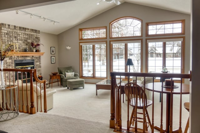 living room with vaulted ceiling, carpet floors, a fireplace, and rail lighting