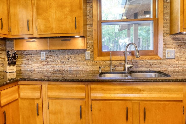 kitchen with sink, dark stone counters, and backsplash