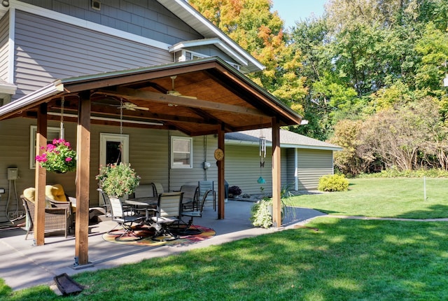 rear view of property featuring ceiling fan, a patio, and a yard