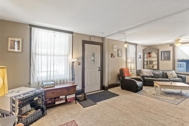 carpeted living area with a textured ceiling, a ceiling fan, and baseboards