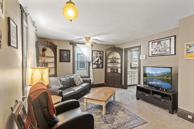 carpeted living area featuring baseboards, a ceiling fan, and a textured ceiling