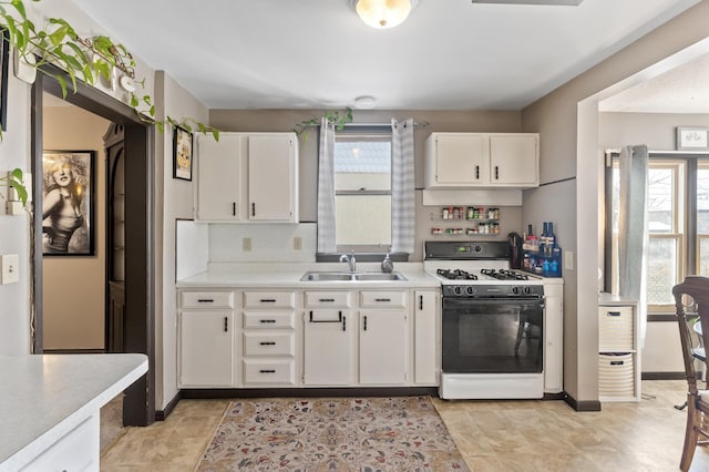 kitchen with white cabinetry, light countertops, a sink, and gas range oven