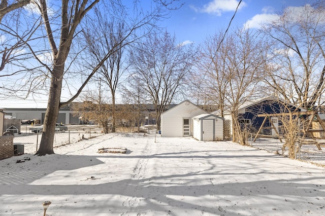 snowy yard with an outbuilding, fence, and a shed