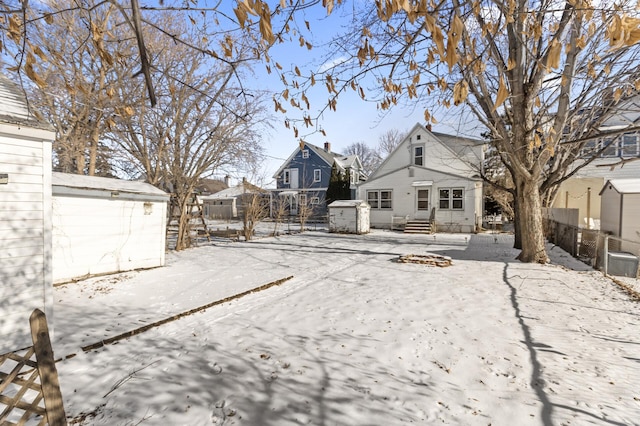 yard layered in snow featuring an outdoor structure, fence, and a shed