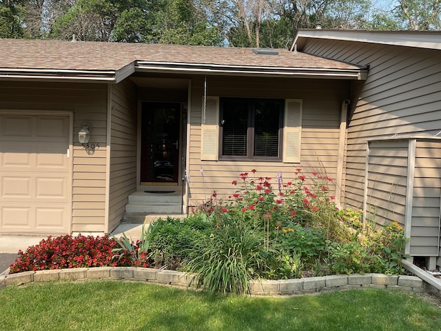 view of exterior entry featuring a lawn and a garage