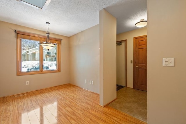 spare room featuring light wood-type flooring and a textured ceiling