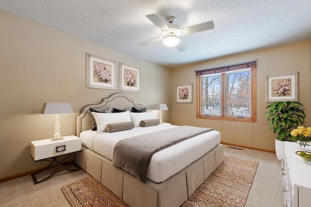 bedroom with a textured ceiling, ceiling fan, and light carpet