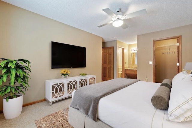 carpeted bedroom with a closet, connected bathroom, ceiling fan, and a spacious closet